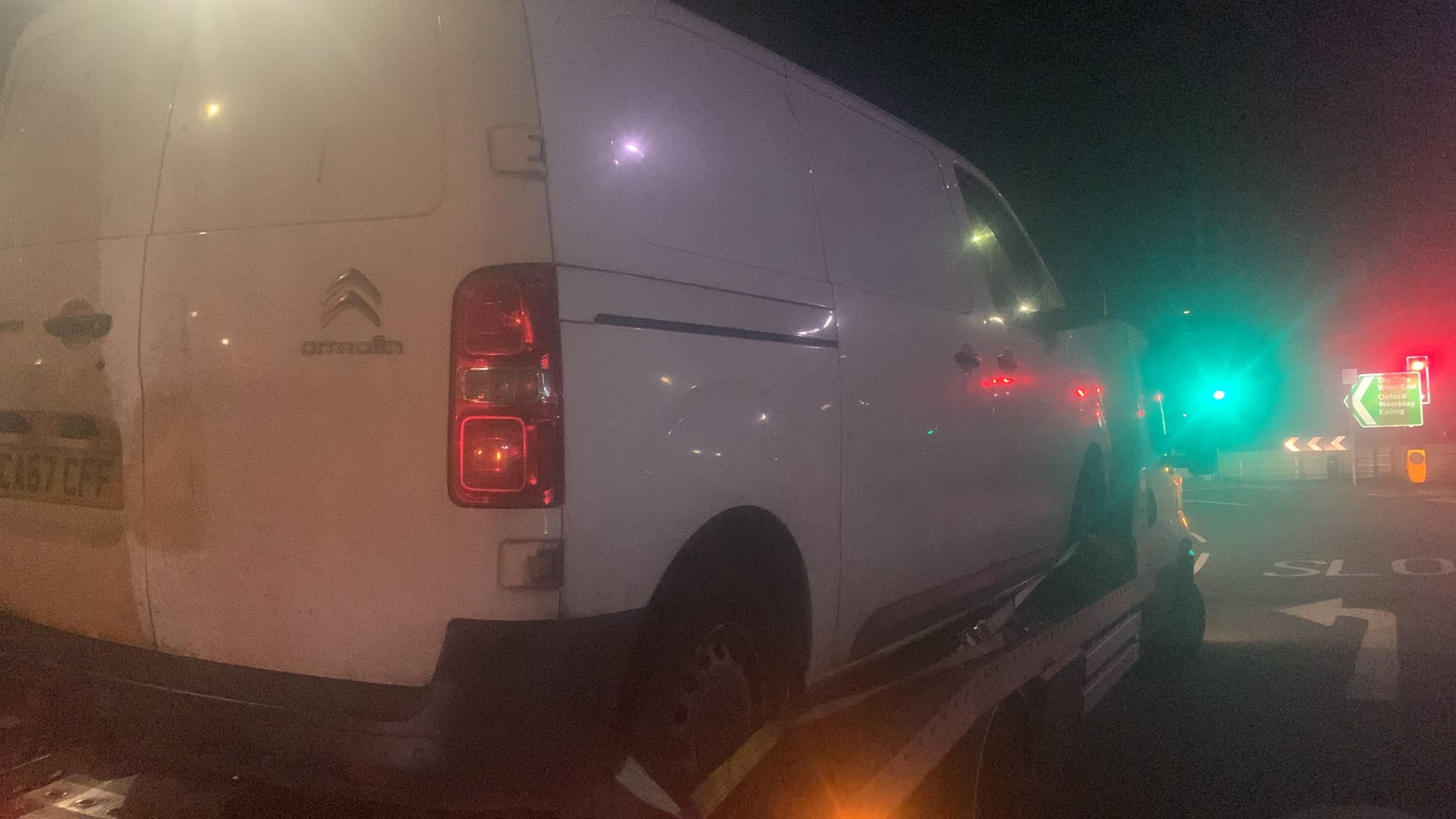 White commercial van on a recovery truck at night