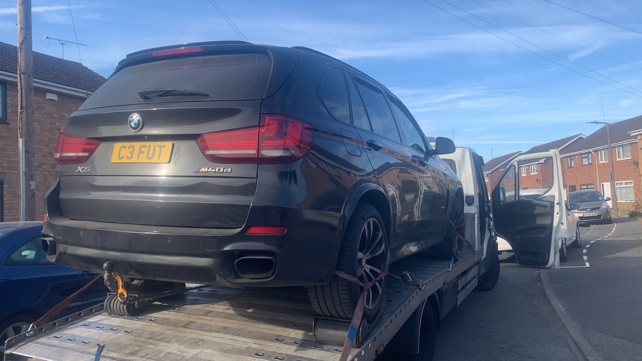 Black BMW SUV secured on a flatbed recovery truck